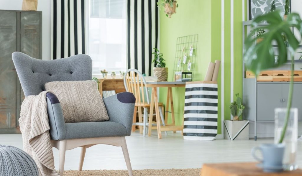 gray chair with a beige throw pillow and blanket