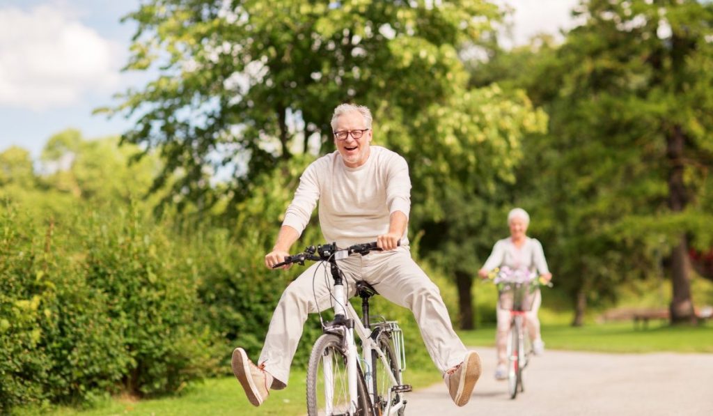happy senior couple riding a bicycle in the park and enjoying life